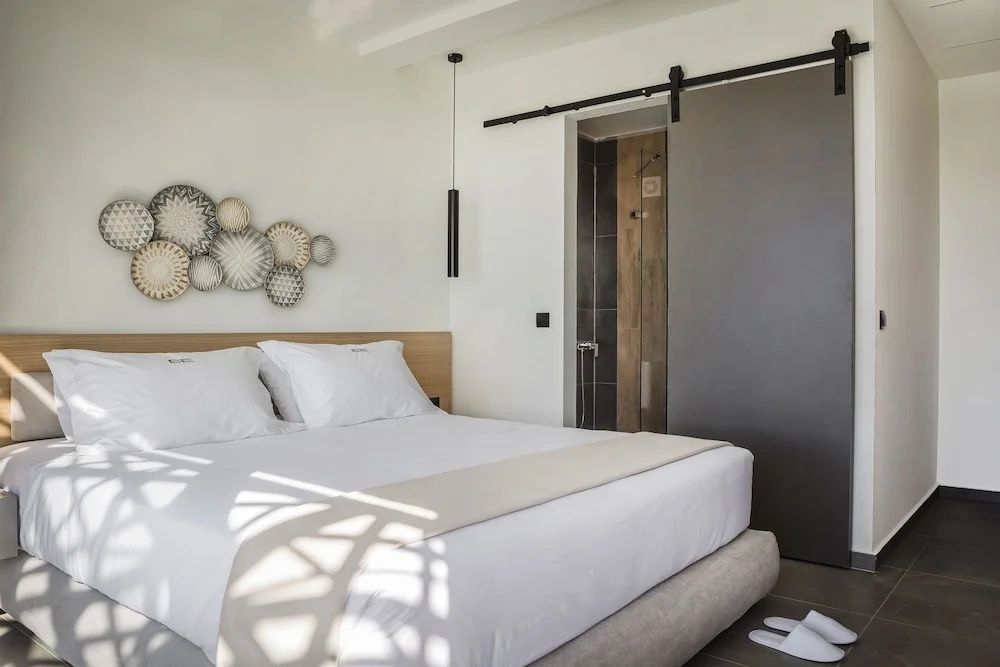 Helles Schlafzimmer mit großem Doppelbett, Wanddekoration und Schiebetür.