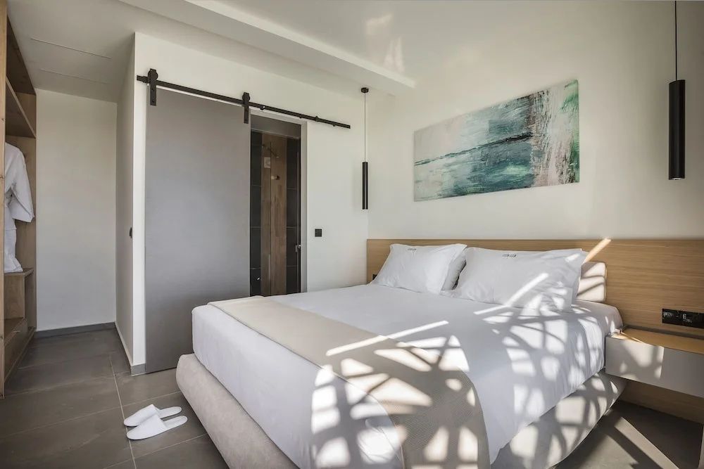 Schlafzimmer mit Doppelbett, Wandbild und Schiebetür zum angrenzenden Raum.