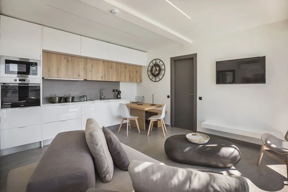 Wohnbereich mit integrierter Küchenzeile, Esstisch, Sofa und Fernseher.