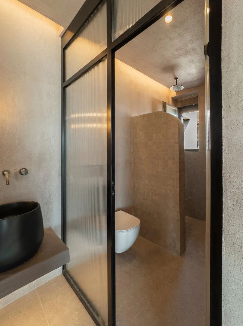 Badezimmer mit schwarzem Waschbecken, Glasabtrennung und Dusche.
