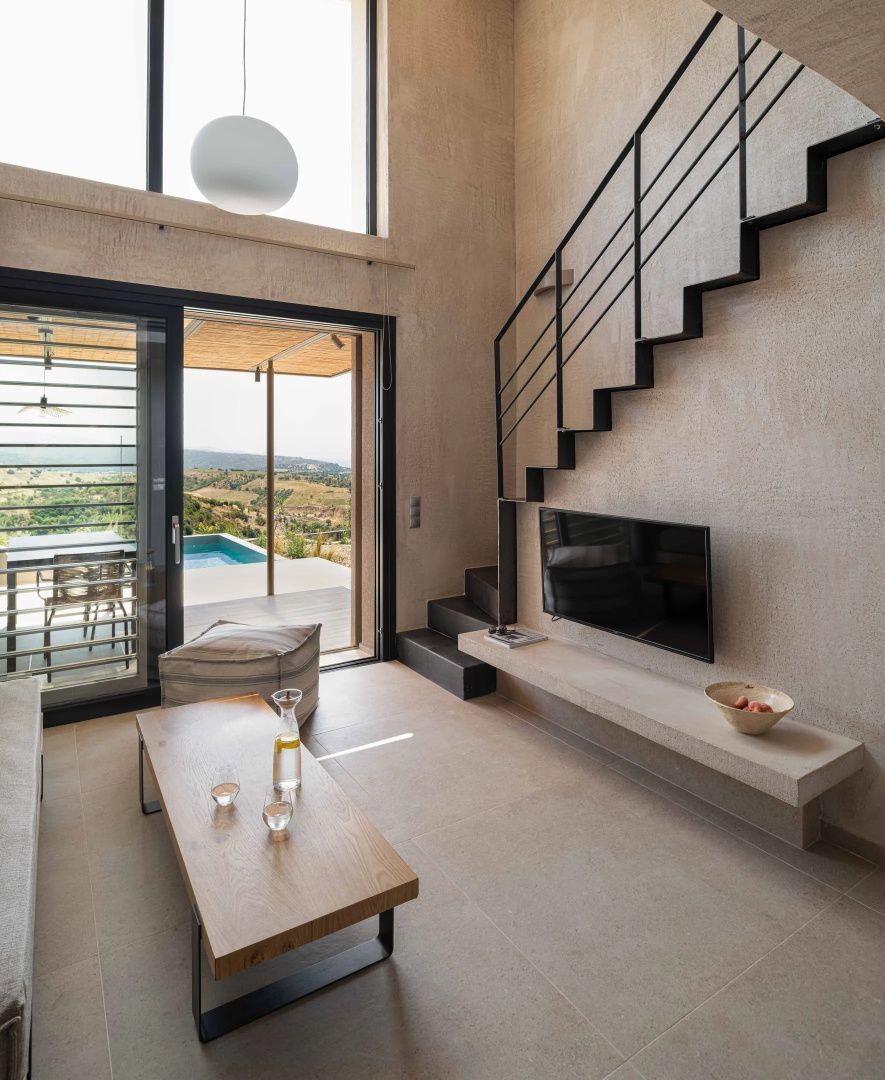 Modernes Wohnzimmer mit Holzcouchtisch, Treppe, Fernseher und Blick auf die Terrasse.