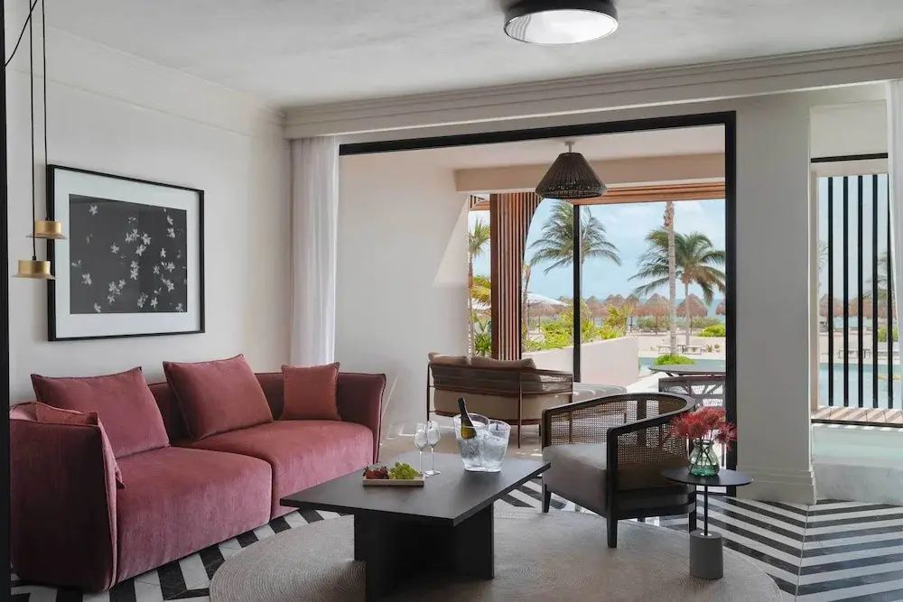 Moderner Wohnbereich einer Suite mit rosafarbenem Sofa, Sessel und Blick auf die Terrasse.