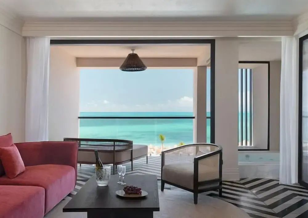 Wohnbereich einer Suite mit direktem Blick vom Balkon auf das türkisfarbene Meer.