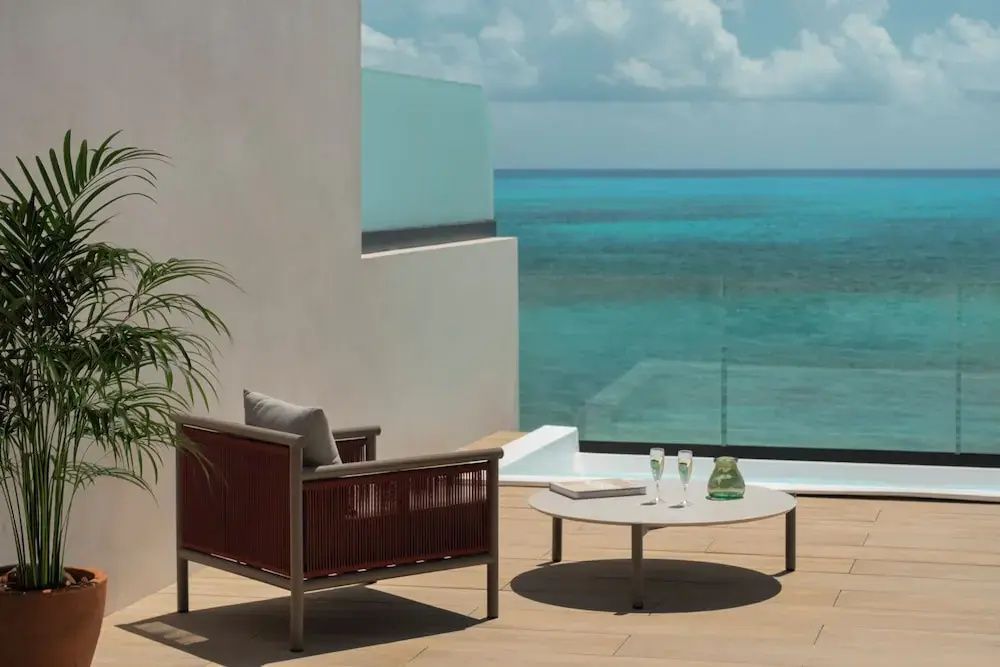 Sonnenterrasse mit einem Sessel, einem kleinen Tisch und Blick auf das Meer.
