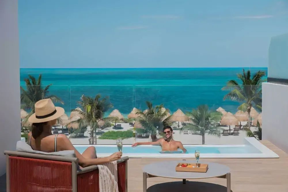 Terrasse mit eigenem Pool und Blick auf das türkisblaue Meer und den Sandstrand.