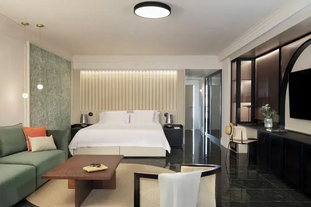 Geräumiges Hotelzimmer mit Doppelbett, Sitzbereich und dunklem Fliesenboden.