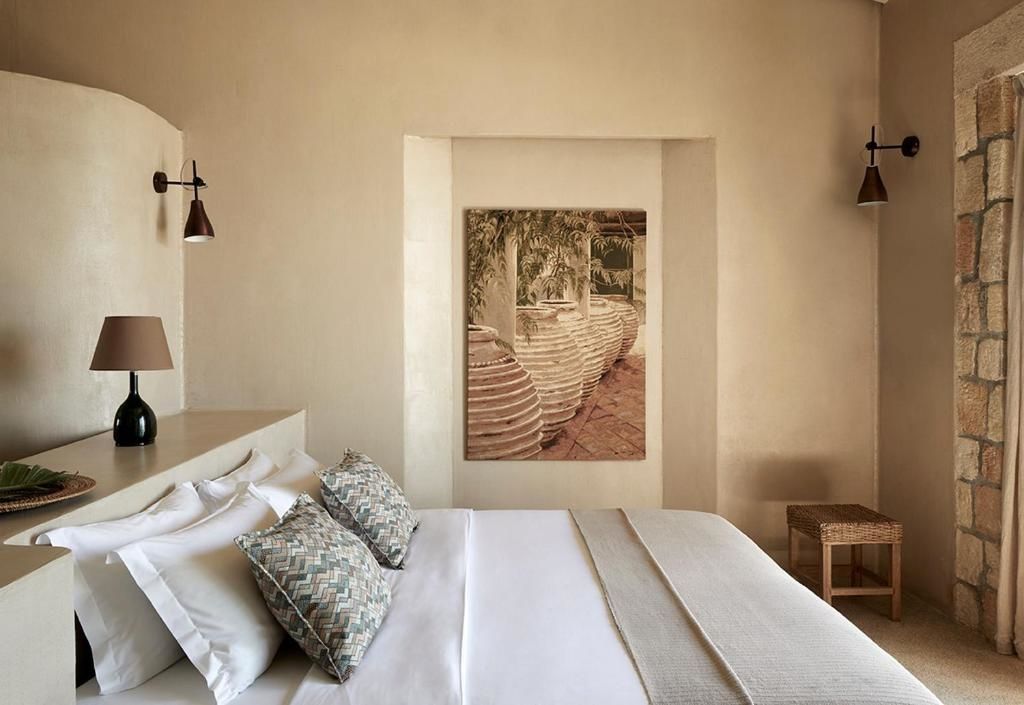 Doppelbett mit weicher Bettwäsche und Kissen in einem hellen Hotelzimmer.