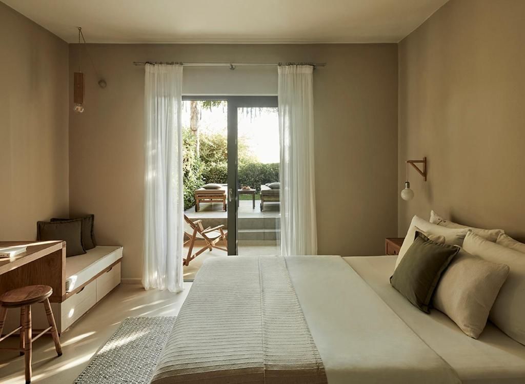 Helles Schlafzimmer mit Doppelbett und Blick durch die Terrassentür ins Grüne.