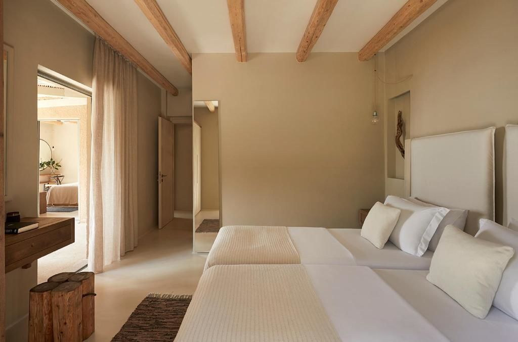 Helles Hotelzimmer mit Holzbalkendecke, zwei Betten und einem langen Spiegel an der Wand.