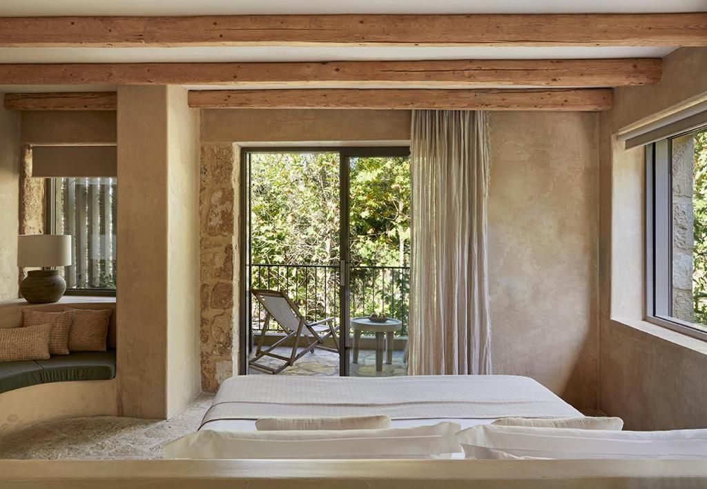 Blick aus dem Schlafzimmer auf eine private Terrasse mit Liegestuhl.