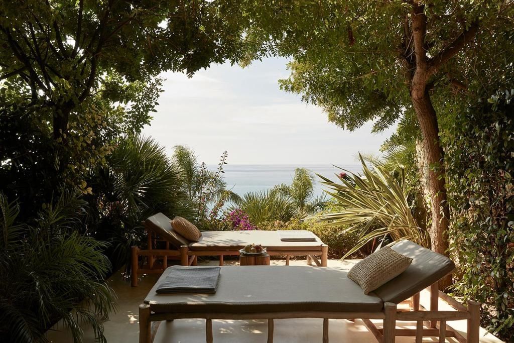 Terrasse im Grünen mit zwei gemütlichen Sonnenliegen und Blick auf das Meer.