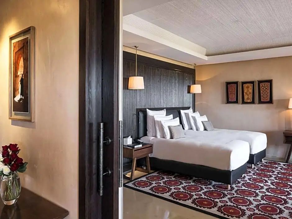 Hotelzimmer mit zwei Einzelbetten, dunkelbrauner Holzwand und gemustertem Teppich.