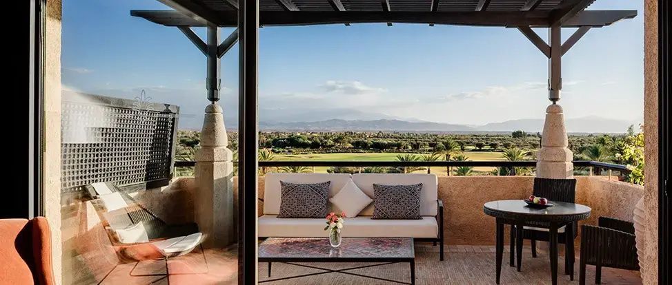 Überdachte Terrasse mit Sofa und Blick auf einen Golfplatz sowie entfernte Berge.
