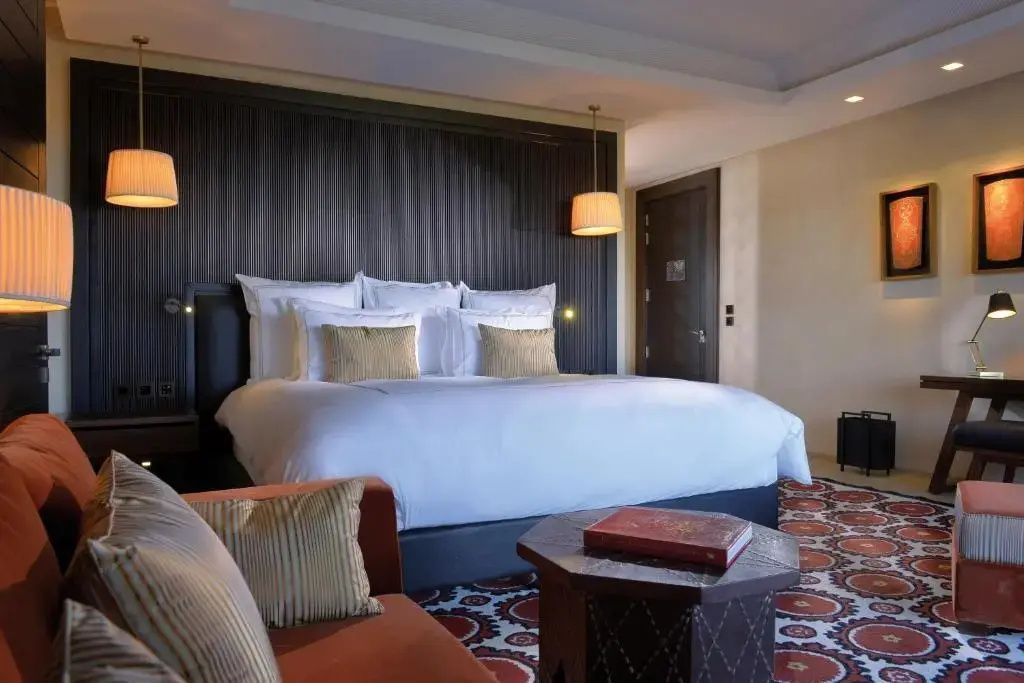 Großes Doppelbett mit weißer Bettwäsche und dunkler Holzrückwand im Hotelzimmer.
