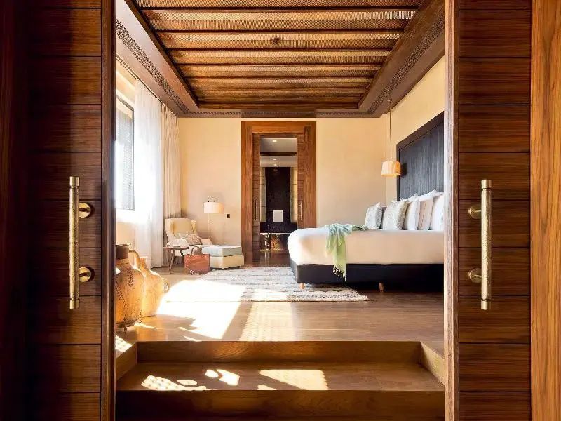 Blick durch einen Türrahmen in ein helles Schlafzimmer mit verzierter Holzdecke.