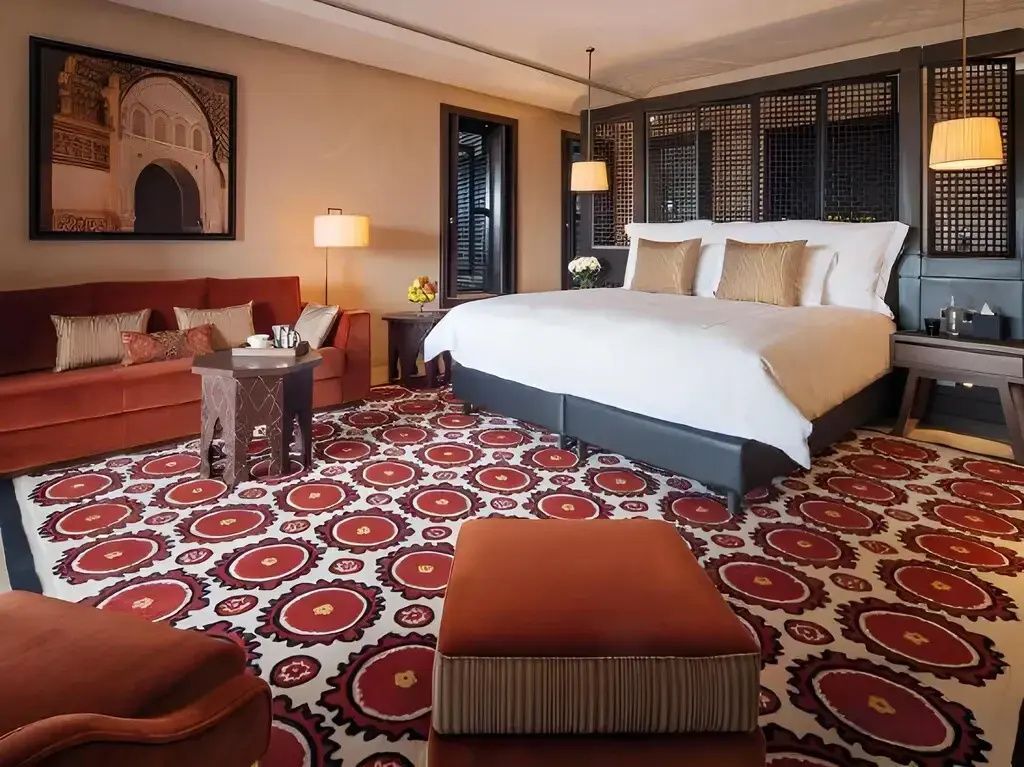 Schlafzimmer mit Doppelbett, rot gemustertem Teppich und rotem Sofa.