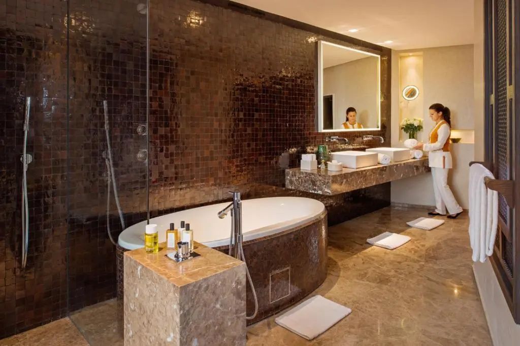 Badezimmer mit Mosaikwand, freistehender Badewanne und Doppelwaschtisch.