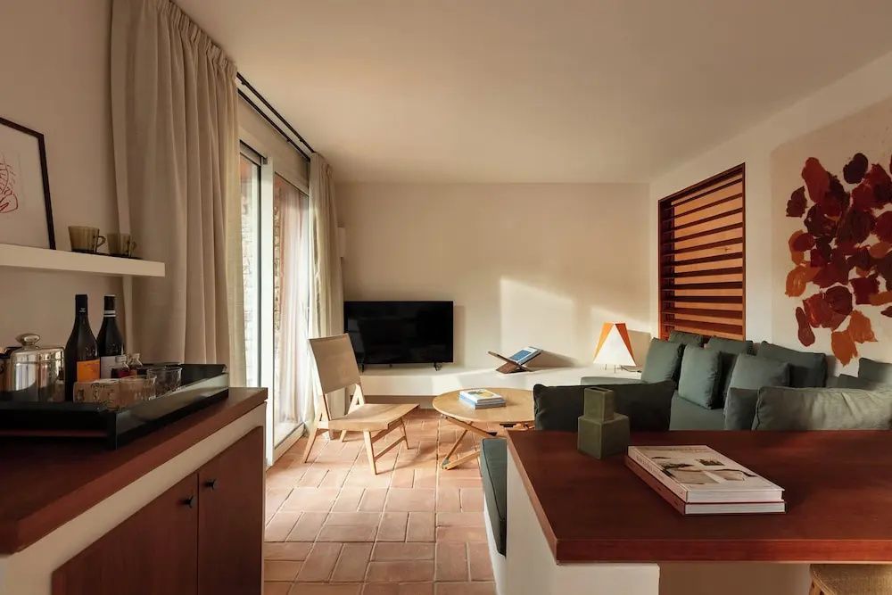 Wohnbereich mit Sofa, Holzstuhl, flachem Couchtisch und Fernseher auf Terrakottafliesen