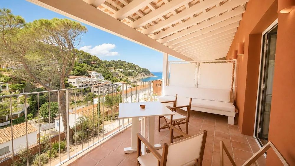 Überdachte Terrasse mit Sitzmöglichkeiten und Blick auf die grüne Küstenlandschaft.
