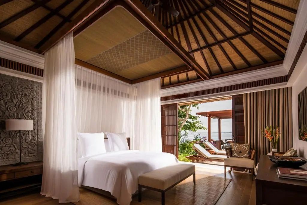 Schlafzimmer einer Villa mit Himmelbett, Holzdecke und geöffneter Tür zur Terrasse