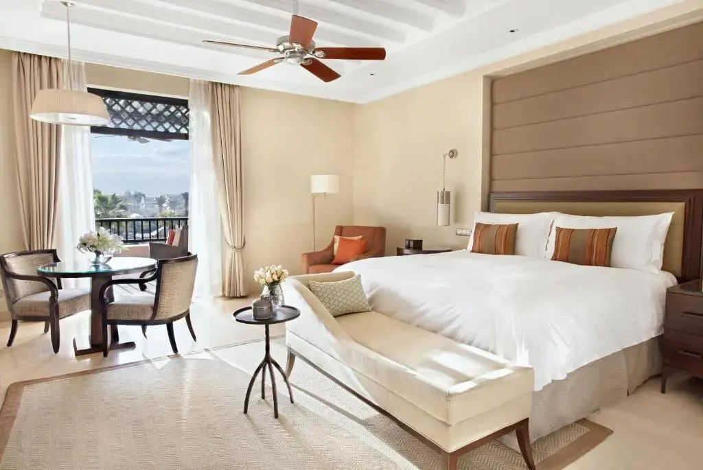 Helles Hotelzimmer mit großem Doppelbett, Deckenventilator und Balkonzugang.