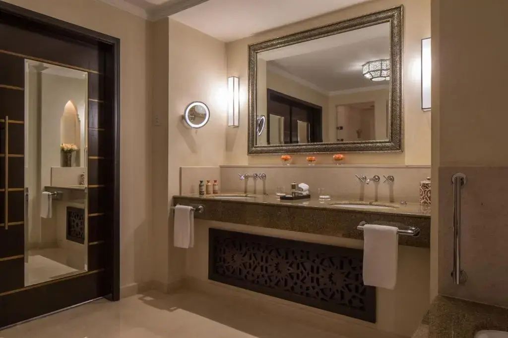 Badezimmer mit zwei Waschbecken, großem Wandspiegel und orientalischen Verkleidungen an den Möbeln.