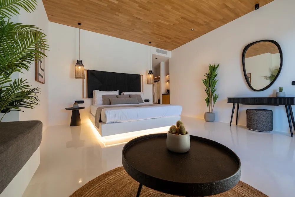 Schlafzimmer mit Doppelbett, Holzdecke und indirekter Beleuchtung am Bett.