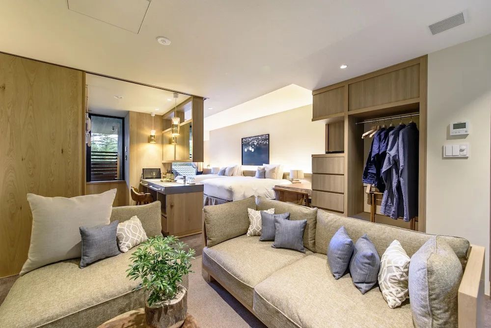 Modern eingerichtetes Hotelzimmer mit gemütlicher Sitzecke und Betten im Hintergrund.