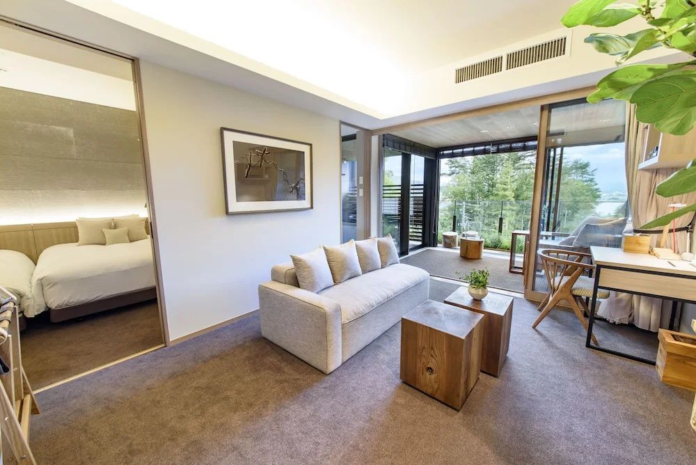 Hell eingerichtetes Wohnzimmer einer Suite mit beigem Sofa und Holzwürfeltischen.
