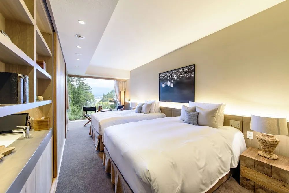Schlafbereich im Hotelzimmer mit zwei Doppelbetten und einem Panoramafenster.