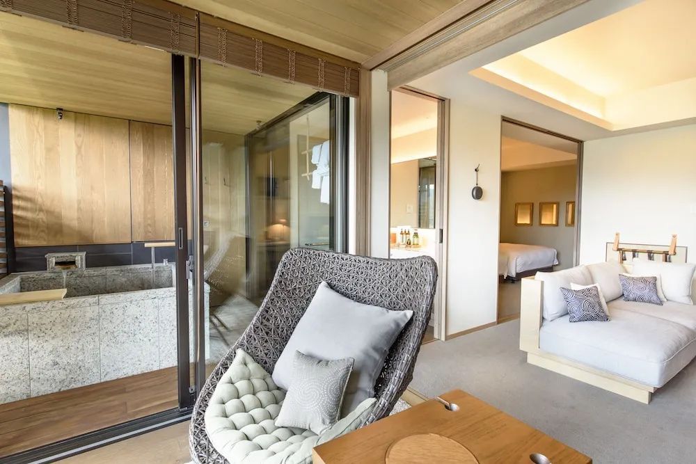Sessel im Wohnbereich einer Suite mit Blick auf die Terrasse und den Schlafbereich im Hintergrund.