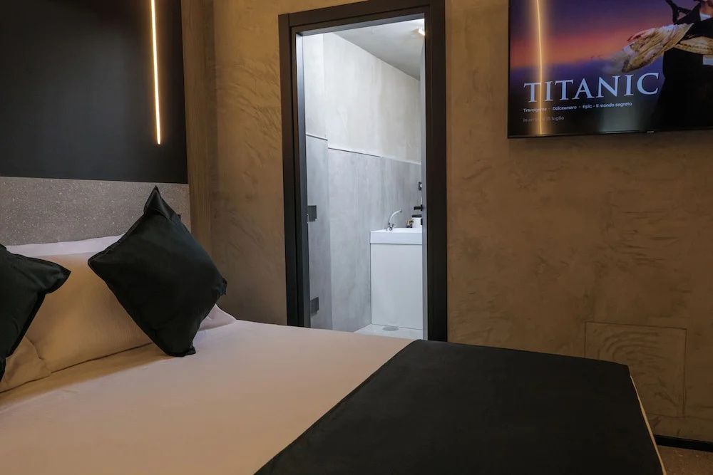 Bett im Zimmer mit freiem Blick durch die offene Tür in das Badezimmer.
