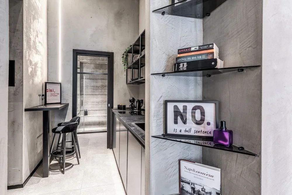 Kleine Küchenzeile mit Barhockern und Glasregalen im modernen Design.