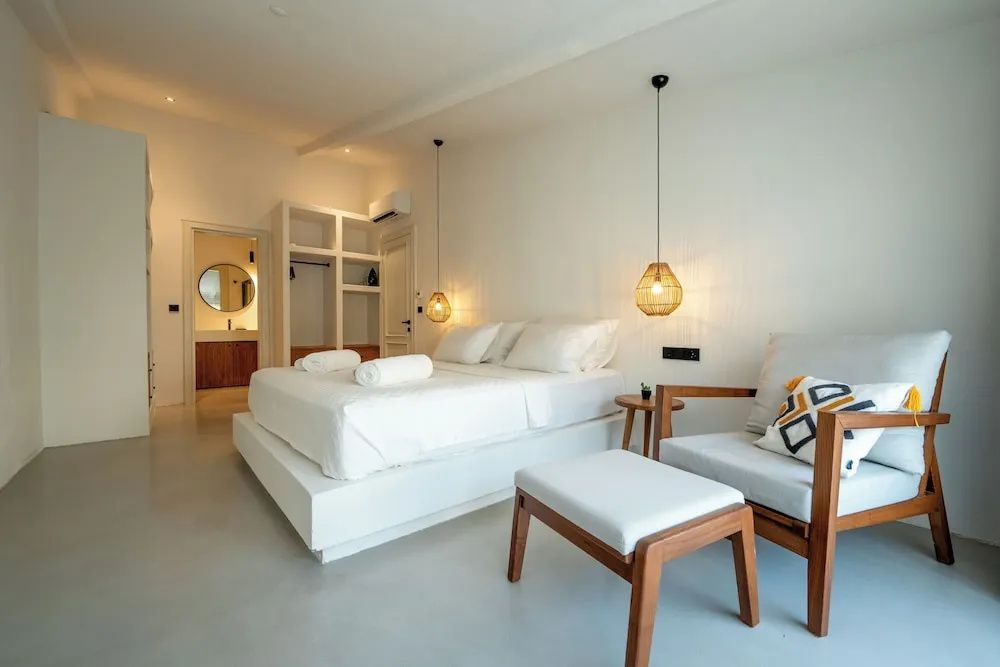 Schlafbereich mit bequemem Sessel, großem Doppelbett und Durchgang zum Badezimmer.