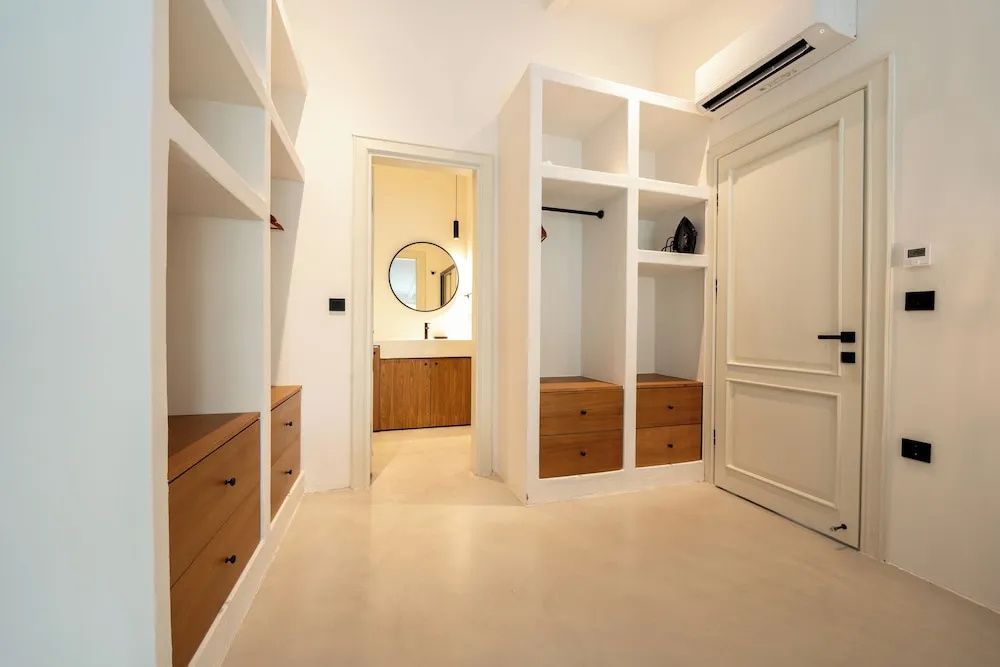 Ankleidebereich mit hellem Einbauschrank aus Holz und Blick auf das Badezimmer.