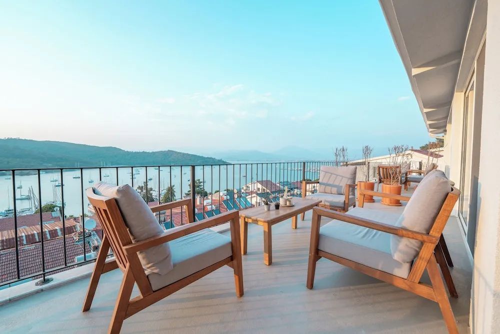 Möblierte Terrasse aus Holz mit Panoramablick auf die Bucht und Berge.