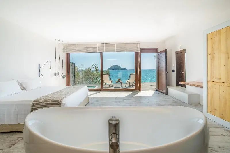 Blick aus dem Hotelzimmer durch eine Glasfront auf das Meer und eine kleine Insel.