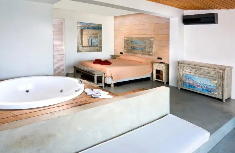 Hotelzimmer mit integriertem Whirlpool, Doppelbett und hellem Holzdekor.