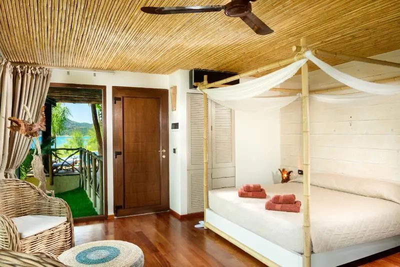 Schlafzimmer mit Holzdecke, Bambus Himmelbett und Zugang zum Balkon.