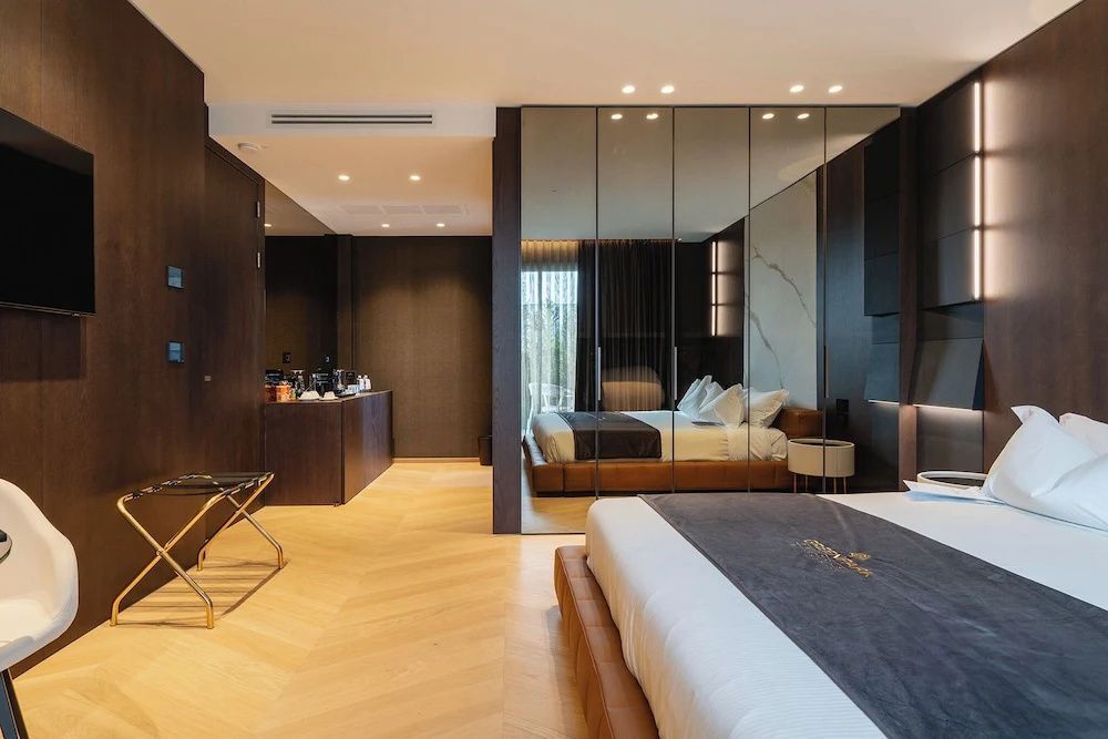 Schlafbereich der Suite mit Doppelbett, Holzboden und Spiegelschrank