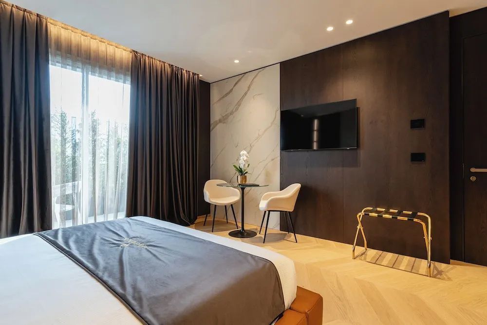 Schlafzimmer mit Doppelbett, einem kleinen Tisch mit zwei Stühlen und Wandfernseher.