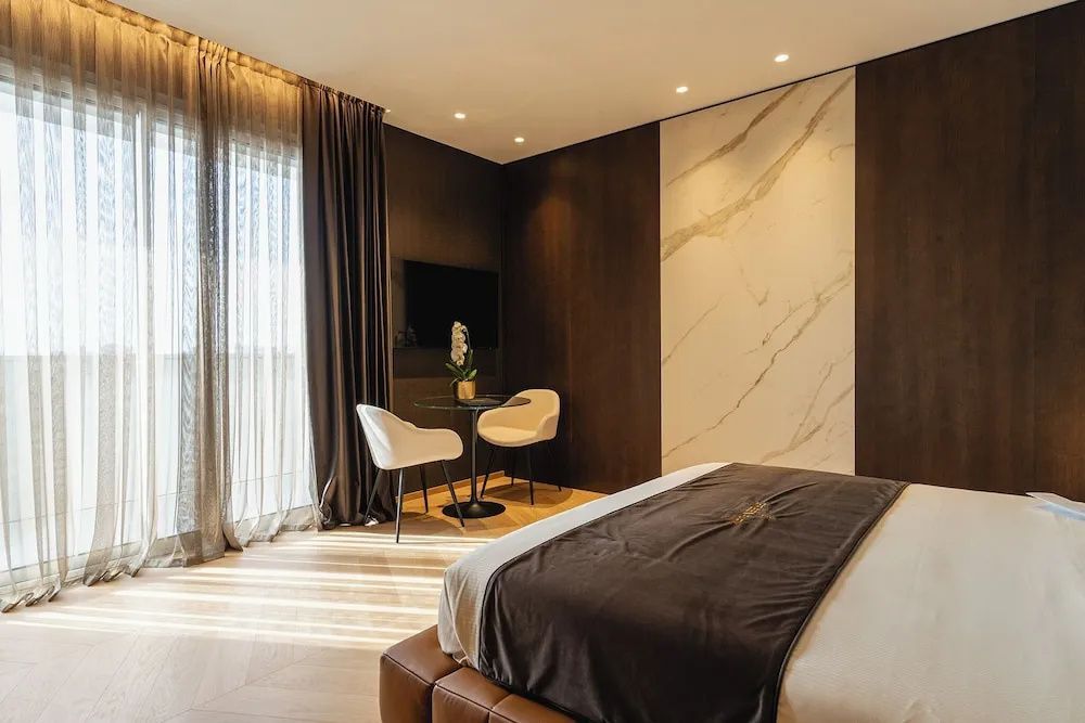 Schlafbereich der Suite mit Doppelbett, dunkler Wandverkleidung und einer kleinen Sitzecke