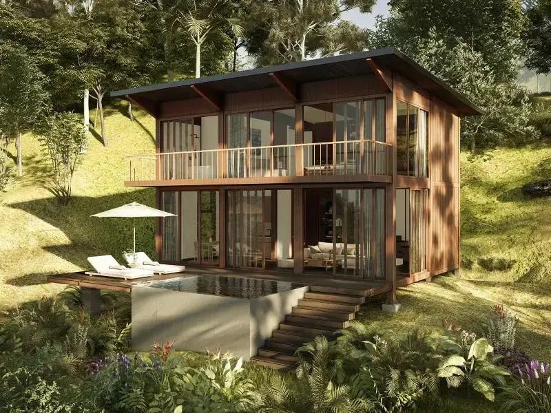 Holzhaus in hanglagiger Natur mit Glasfront, Sonnenschirm und einem kleinen Pool auf der Terrasse.