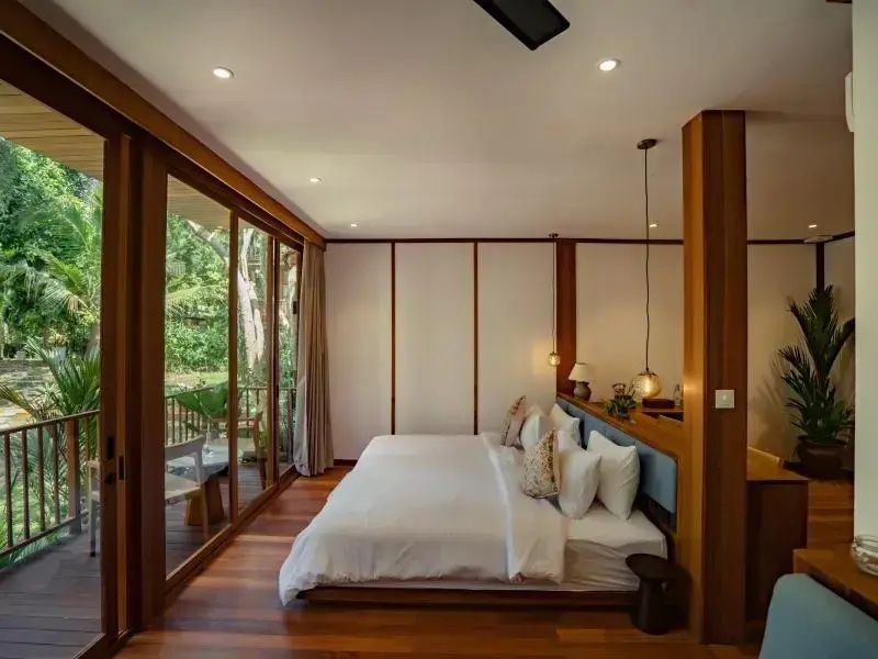 Helles Schlafzimmer mit Holzboden, großem Doppelbett und Glasschiebetüren zum Balkon.