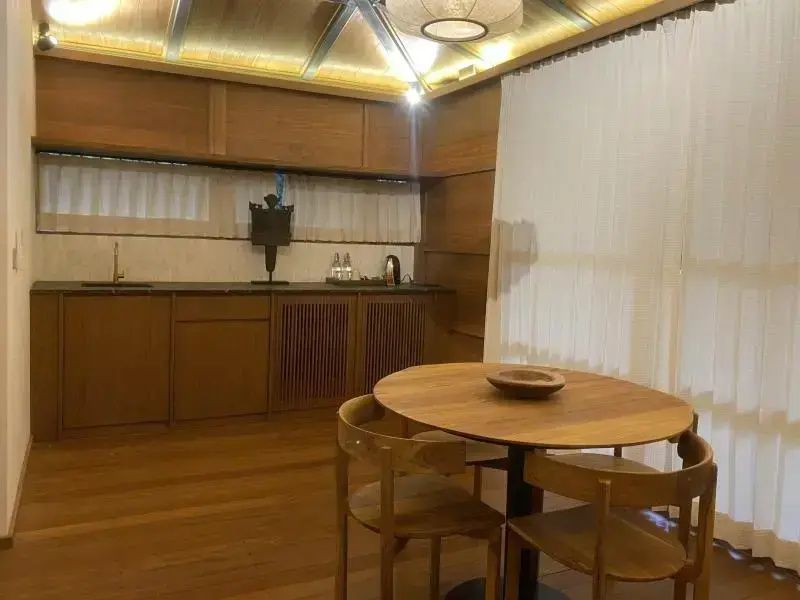 Essbereich aus Holz mit rundem Tisch, Stühlen und einer integrierten Küchenzeile.
