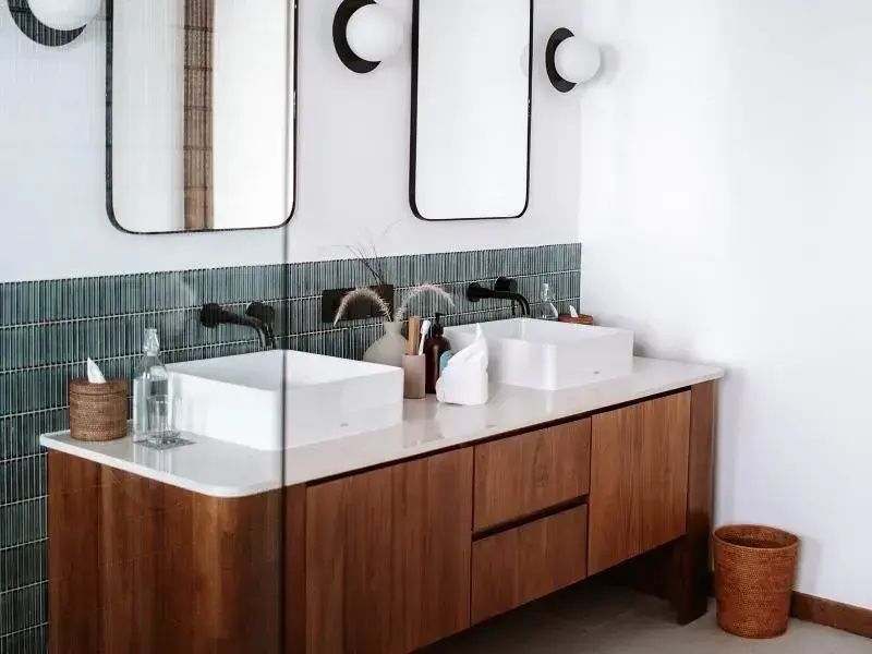 Badezimmer mit Doppelwaschtisch auf einem Unterschrank aus Holz und zwei rechteckigen Spiegeln.