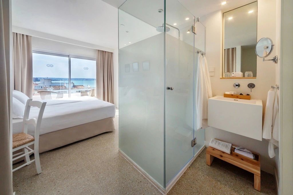 Moderne Glasduschkabine und Waschtisch im offen gestalteten Hotelzimmer.