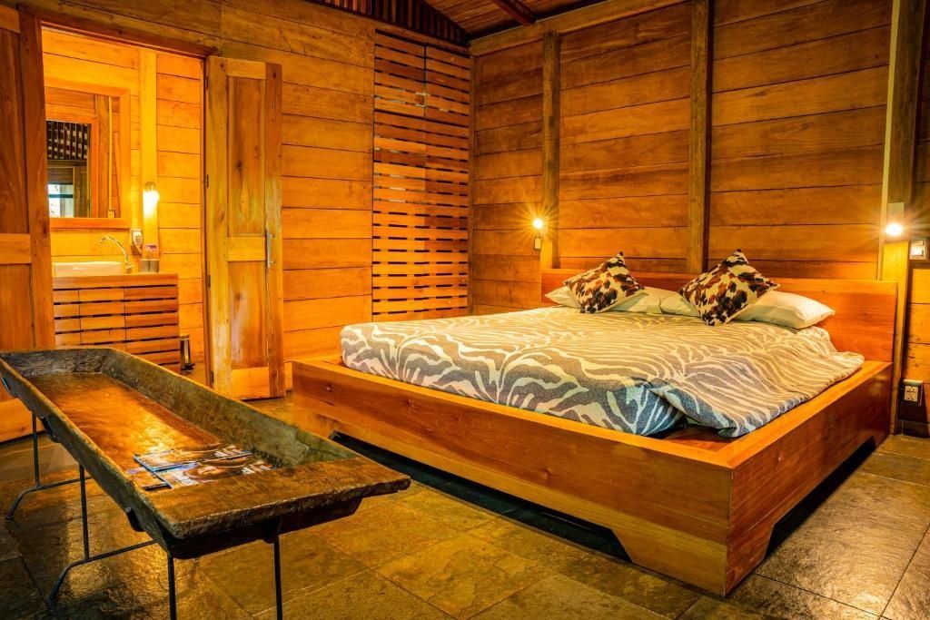 Holzverkleidetes Schlafzimmer mit einem großen Doppelbett und Zebra Muster Kissen.