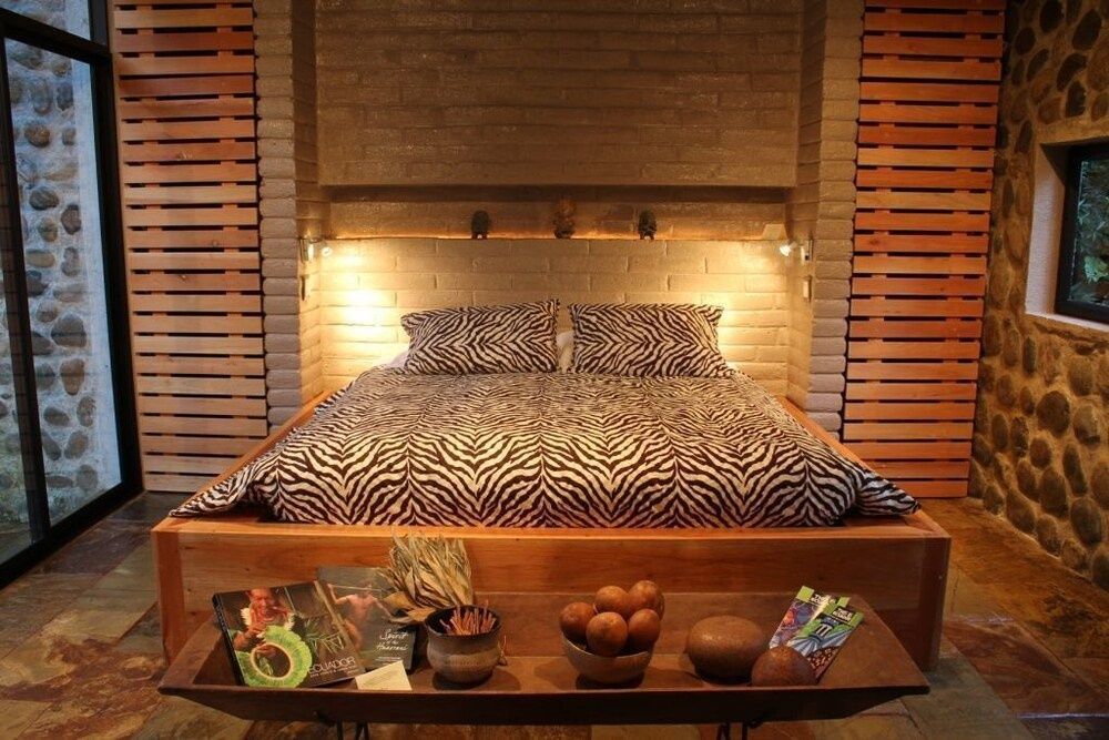 Doppelbett mit Zebrabettwäsche an einer gemauerten Wand mit warmer Beleuchtung.