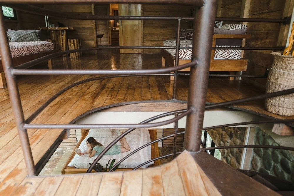 Blick über eine Wendeltreppe auf ein Bett im Erdgeschoss einer Holzunterkunft.